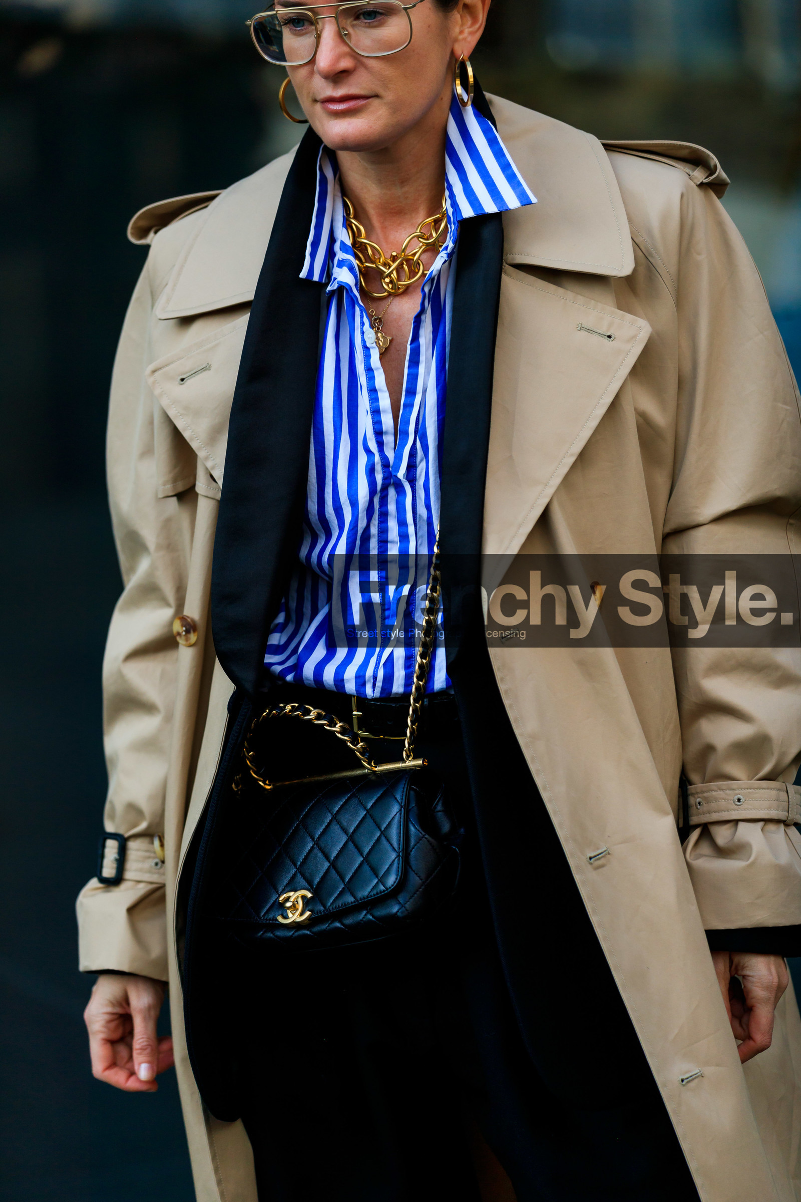 Lucy Chadwick, beige trench coat, black leather bag, black jacket, black pants, blue shirt, white shirt, striped shirt, aviator glasses, golden earrings, golden necklace, golden frame sunglasses, big chain necklace, hoop earrings, multi charms necklace, multi necklace, crossbody bag, chanel bag, quilted bag, fashion week, frenchystyle, FW, jonathan paciullo, street style, NYFW, NEW YORK, AUTUMN WINTER 2020-2021, FALL WINTER 2020-2021, FW 20-21, vertical, detail, atmosphere details