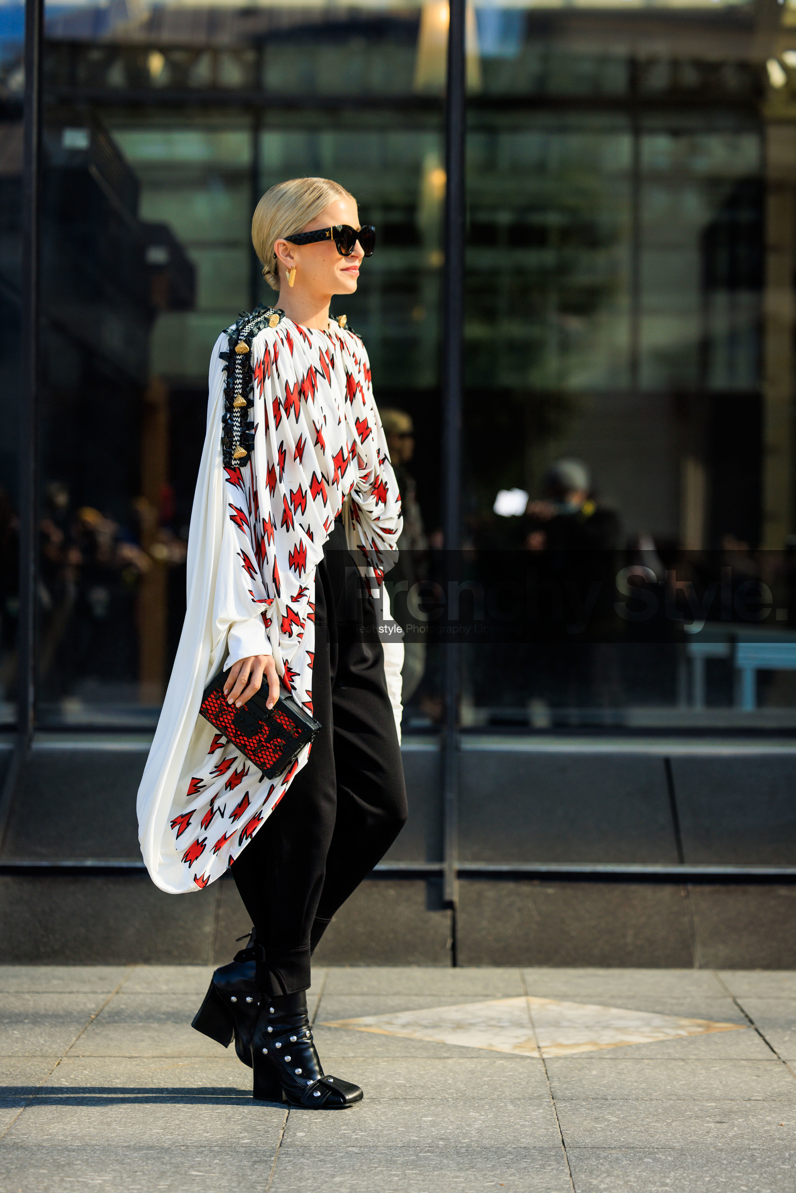 black sunglasses, printed cape, white cape, louis vuitton, louis vuiton clutch, black clutch, black trousers, highwaist pants, black boots, leather boots, heeled boots, golden earrings, flower detail cape, pleated cape, caro daur, street style, jonathan paciullo, FW, frenchystyle, fashion week, AUTUMN WINTER 2022-2023, FALL WINTER 2022_2023, FW 22-23, PFW, PARIS, full length, vertical