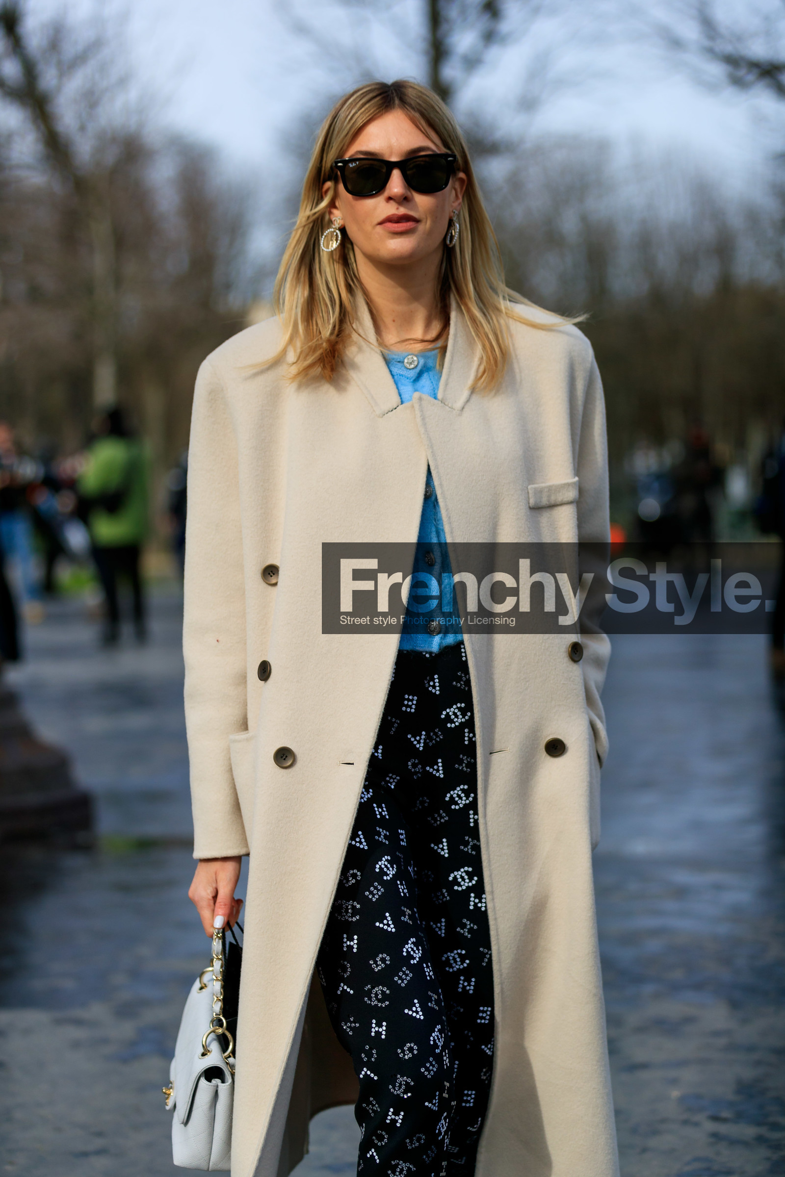 camille charriere, light beige coat, white leather bag, quilted bag, light blue cardigan, rayban sunglasses, black pants, black sunglasses, logo printed pants, tight pants, strassed pants, strassed earrings, round shape earrings, logo earrings, chanel bag, chanel earrings, chanel pants, chanel cardigan, hand bag, fashion week, frenchystyle, FW, jonathan paciullo, street style, PFW, PARIS, vertical, atmosphere details, detail
