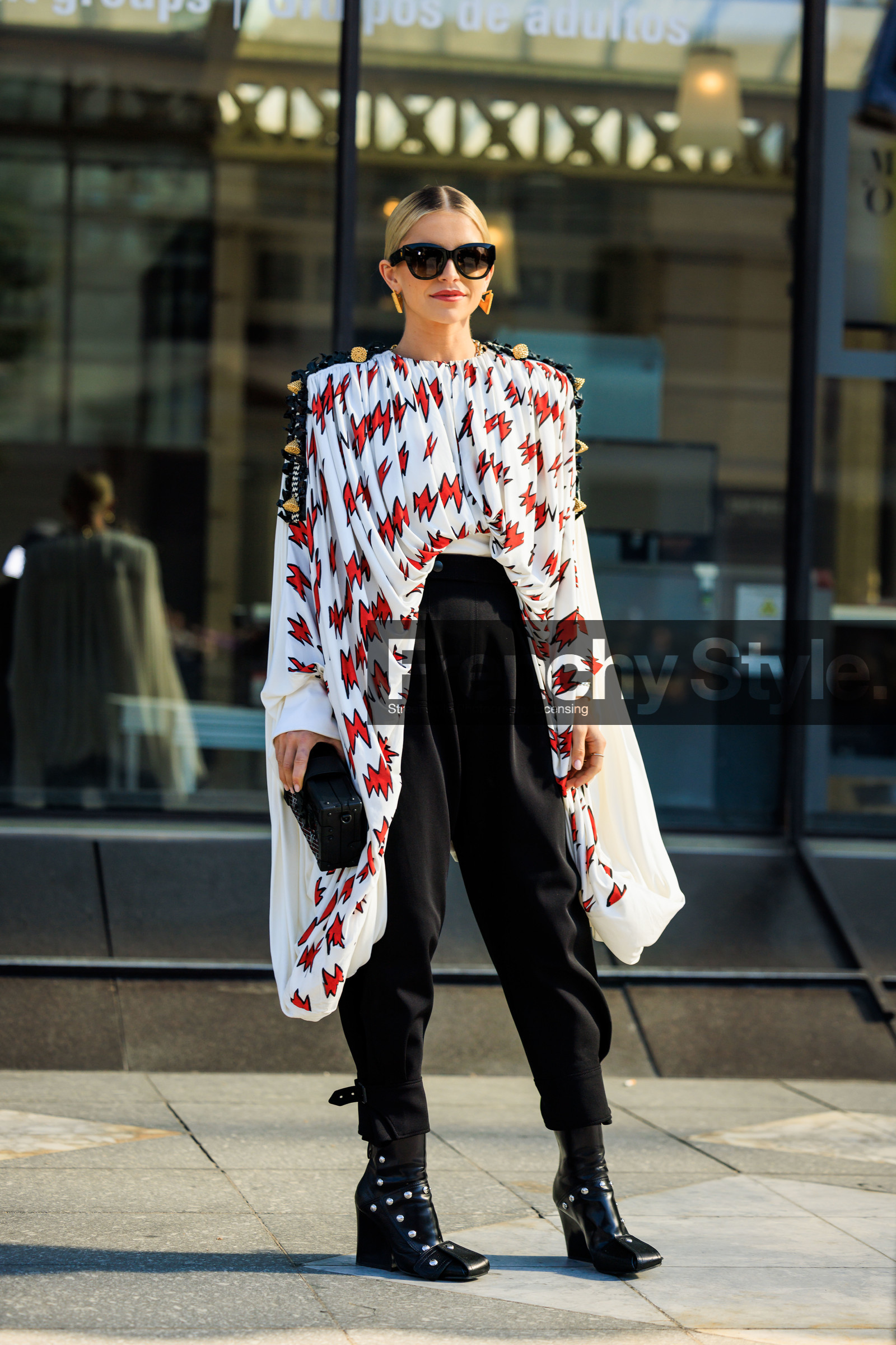 black sunglasses, printed cape, white cape, louis vuitton, louis vuiton clutch, black clutch, black trousers, highwaist pants, black boots, leather boots, heeled boots, golden earrings, flower detail cape, pleated cape, caro daur, street style, jonathan paciullo, FW, frenchystyle, fashion week, AUTUMN WINTER 2022-2023, FALL WINTER 2022_2023, FW 22-23, PFW, PARIS, full length, vertical