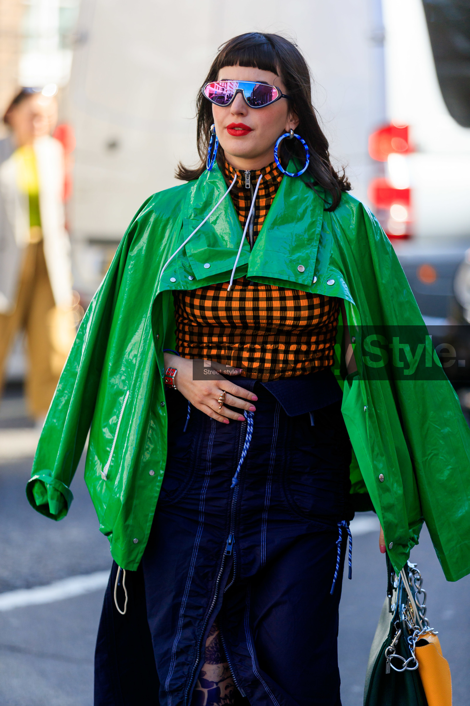 future shape sunglasses, rainbow sunglasses, hoop earrings, plastic earrings, blue earrings, green jacket, waterproof jacket, loewe jacket, polish jacket, checked top, black and orange top, zipped top, zipped skirt, navy blue skirt, technical fabric skirt, chain strap bag, silvered chain strap bag, fashion week, frenchystyle, FW, jonathan paciullo, street style, vertical, detail, atmosphere details