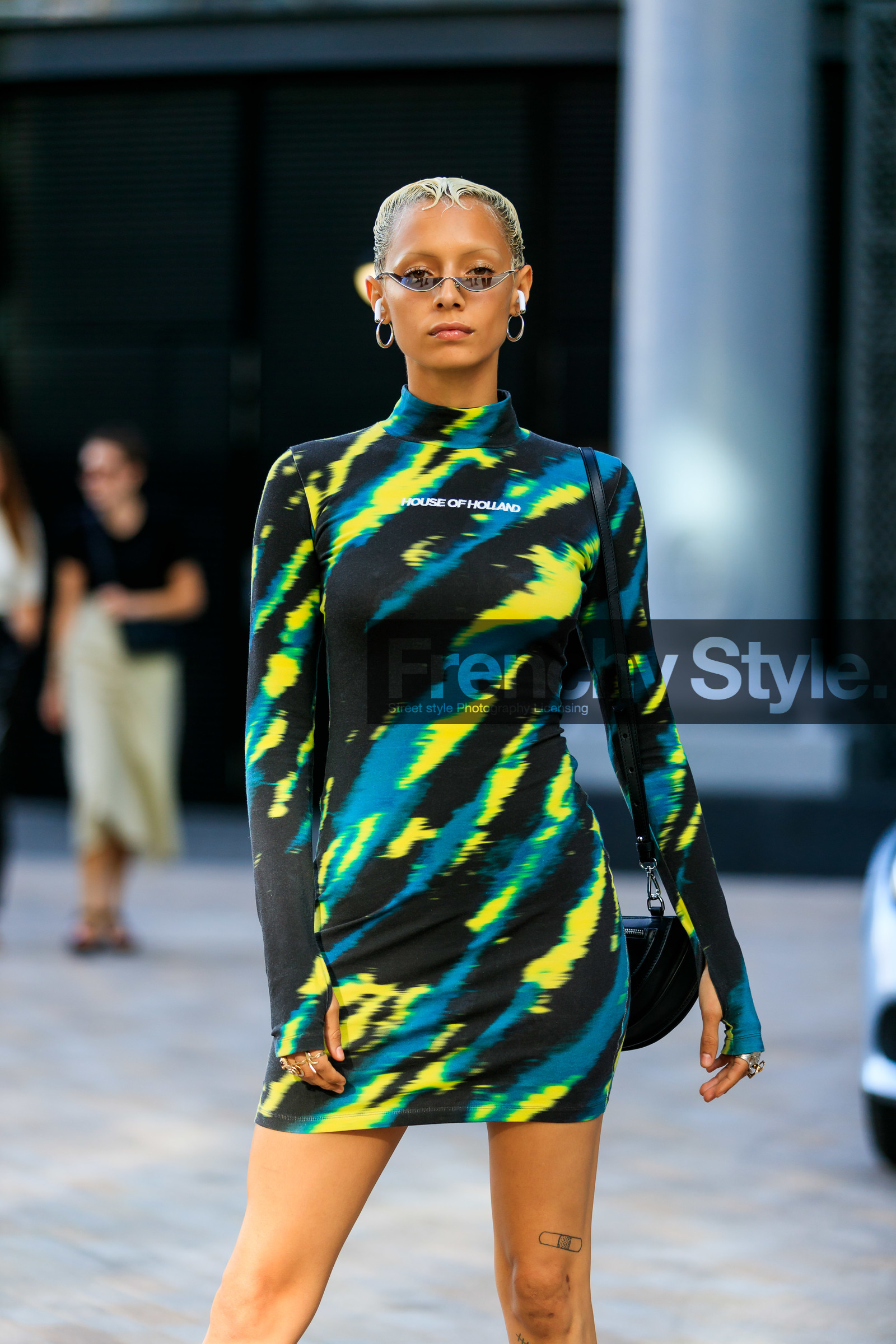 butterfly sunglasses, smoked sunglasses, thin sunglasses, dyed hair, short hair, airpod, hoop earrings, house of holland dress, tie and dye dress, black and green dress, turtleneck dress, future shape sunglasses, thin eyebrows, tight dress, long sleeves dress, house of holland bag, black leather bag, shoulder bag, round bag, mini dress, silvered boots, high heels boots, high boots, squared toed shoes, fashion week, frenchystyle, FW, jonathan paciullo, street style, vertical, detail, atmosphere details
